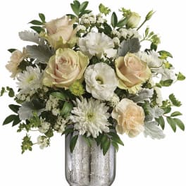 Cream roses and white blooms arranged in a clear glass vase