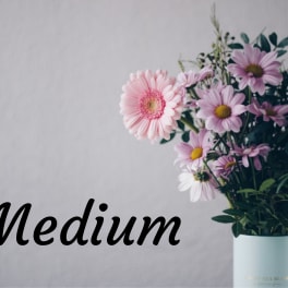 Bouquet of pink and lavender daisies in a light blue vase