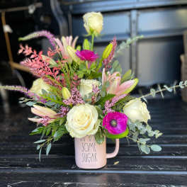 Pink mug vase with white roses, lilies, and a magenta anemone