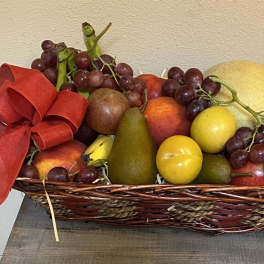 Fruit basket with grapes, pears, apples, and a red ribbon bow