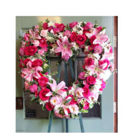 Heart-shaped floral wreath with pink lilies and roses on an easel