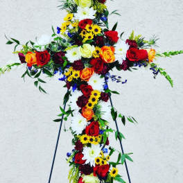 Cross-shaped floral tribute with red, orange, yellow, and white flowers