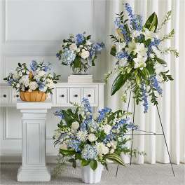 Blue and white floral arrangements in vases and a basket