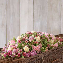 Pink and cream floral arrangement in a wicker casket spray basket