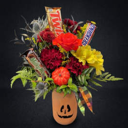 Halloween bouquet in a jack-o'-lantern vase with candy bars and bright flowers