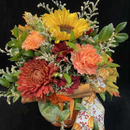 Bouquet with a sunflower, orange mums, and autumn ribbon on a black background