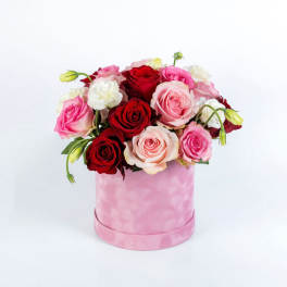 Pink and red roses arranged in a pink round box