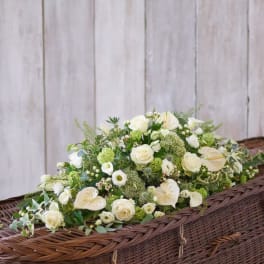White floral casket spray with roses, calla lilies, and green accents