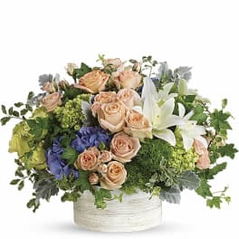 Peach roses and white lilies in a round white vase