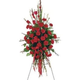 Tall standing spray of red carnations with ribbon on an easel