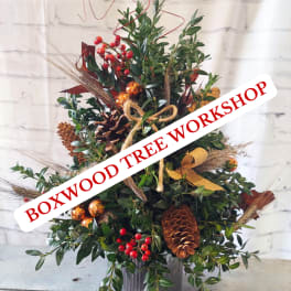 Holiday arrangement with pinecones, red berries, and gold ornaments in a container
