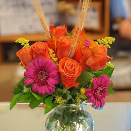 Orange roses and pink gerbera daisies in a clear glass vase