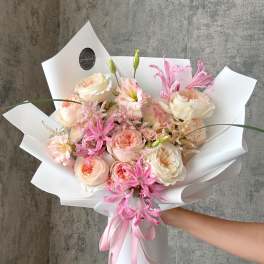 Pink and cream bouquet wrapped in white paper with a pink ribbon