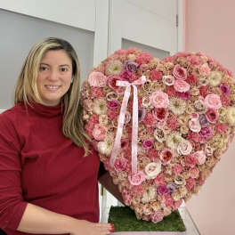 Heart-shaped pink floral arrangement with a ribbon bow