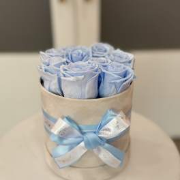 Blue roses arranged in a round hat box with a satin ribbon