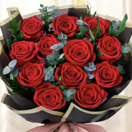 Bouquet of red roses wrapped in black paper with a pink ribbon