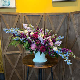 Large mixed bouquet in a white vase with purple, pink, and blue flowers