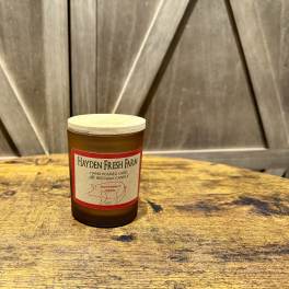 Amber candle jar with a wooden lid on a rustic table