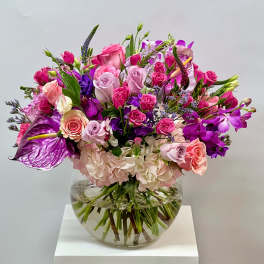 Mixed pink and purple flower arrangement in a clear glass vase