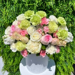 Round bouquet of pink, white, and green flowers in a white vase