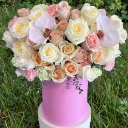 Pink and cream rose bouquet in a pink hat box with orchid accents