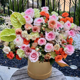 Large mixed bouquet in a gold box with pink and orange blooms