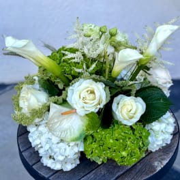 White floral arrangement with roses, calla lilies, and hydrangeas