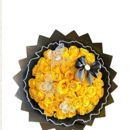 Bouquet of yellow roses wrapped in black paper with butterfly decorations