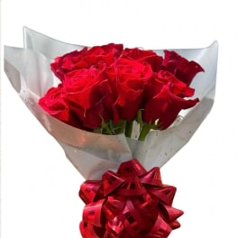 Bouquet of red roses wrapped in translucent paper with a red ribbon bow