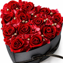 Heart-shaped box of red roses with red petals and gold accents