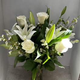 White roses and lilies arranged in a clear glass vase