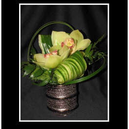 Orchid arrangement in a glittery basket with green foliage
