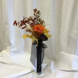 Orange rose arrangement with autumn leaves in a black vase