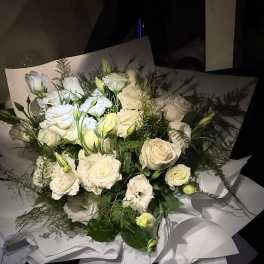 Bouquet of white roses and white lisianthus wrapped in white paper