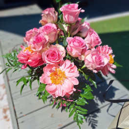 Pink roses and peony-like blooms arranged in a bouquet