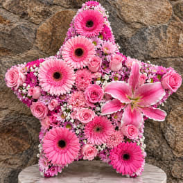 Pink star-shaped floral arrangement with gerbera daisies and roses