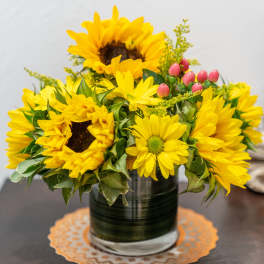 Yellow sunflower and daisy arrangement in a glass vase