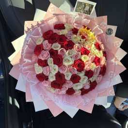 Large bouquet of red, pink, and white roses wrapped in pink paper