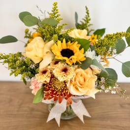 Bouquet of yellow roses, sunflowers, and chrysanthemums in a glass vase