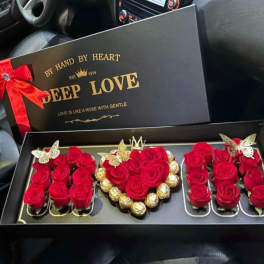 Black gift box with red roses and chocolates arranged inside
