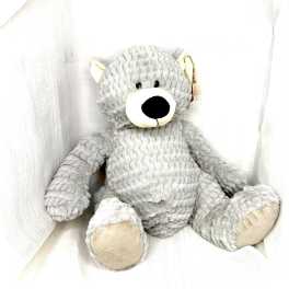 Gray plush teddy bear sitting against white fabric