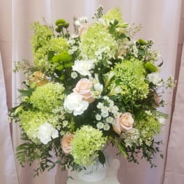 Large bouquet of pale roses, white blooms, and green flowers in a white vase