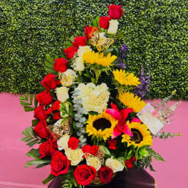Tall floral arrangement with red and white roses and yellow sunflowers in a basket