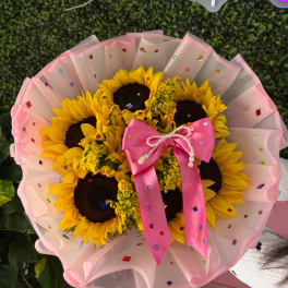 Bouquet of sunflowers wrapped in pink paper with a satin bow