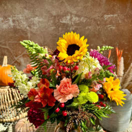 Mixed bouquet with sunflowers, carnations, and alstroemeria in a glass vase