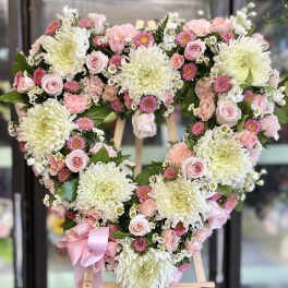 Heart-shaped floral wreath with pink and white flowers on an easel