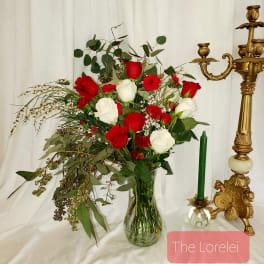 Red and white roses in a clear glass vase with greenery