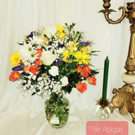 Mixed bouquet of white, yellow, orange, and purple flowers in a glass vase