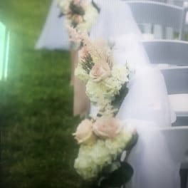 White chairs decorated with pale floral garlands and sheer fabric
