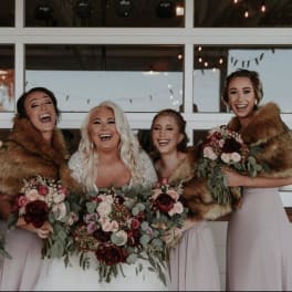 Bride and bridesmaids holding burgundy and blush bouquets
